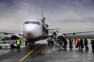 Passengers board Boeing 737 in the rain of low cost airline Ryanair at Beauvais Airport, France. Boarding by stairs from the tarmac is typical for low-cost airlines.